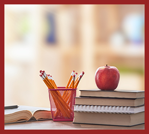 books in stack with apple on top, pencils in container, open book