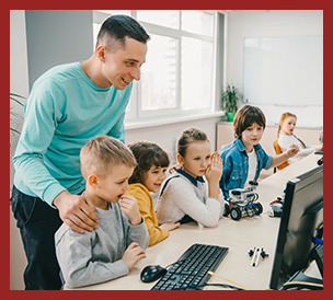 happy young teacher helping his students at computers