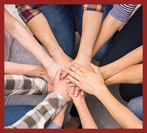 group in circle with hands in the middle on top of each other